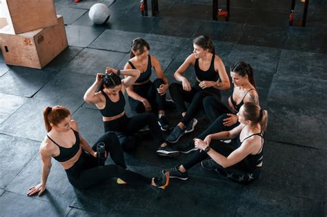 Sentado no chão grupo de jovens esportivos tem dia de crossfit dentro