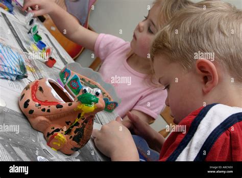 two children decorating clay pots with paints Stock Photo - Alamy