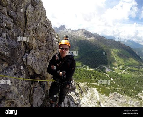 Climber with rope and camera on helmet in the Alps is waiting at the ...