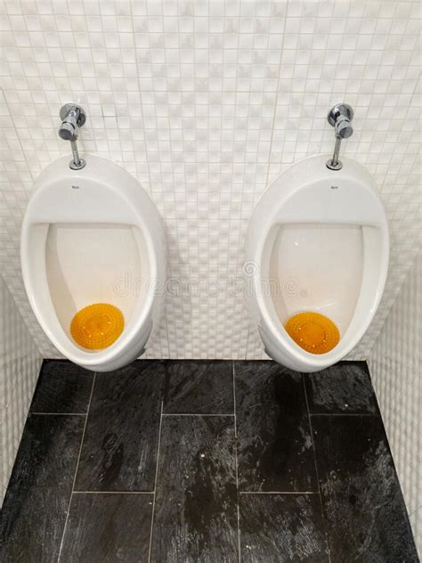 Two Urinals Next To Each Other With A Seperator In Between Stock Image