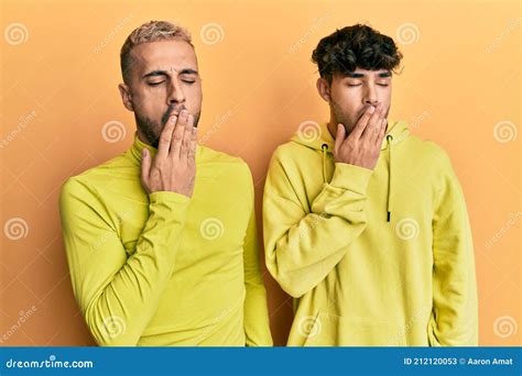 Homosexual Gay Couple Standing Together Wearing Yellow Clothes Bored Yawning Tired Covering