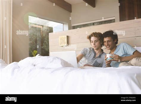 Happy Diverse Gay Male Couple Lying On Bed And Using Laptop At Home Stock Photo Alamy