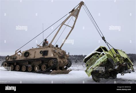 An M88 Armored Recovery Vehicle lifts a truck on snow. Snow and ice can ...