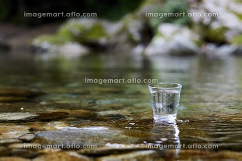 綺麗な川に置かれた水の入ったグラスの写真素材 [193344547] イメージマート