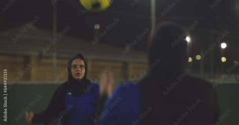 Female Soccer Players In Hijabs Throwing Ball In Soccer Field At Night