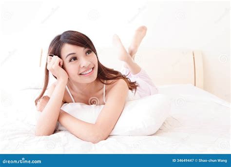 Sourire Heureux De Femme Tout En Se Trouvant Sur Le Lit Image Stock