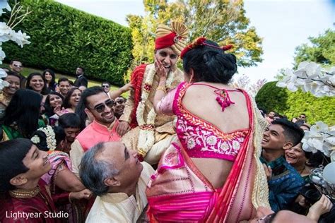 A Woman In A Pink And Gold Sari Is Being Lifted By Her Husband As They