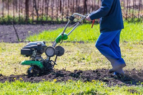 Farmer Man Plows The Land With A Cultivator Preparing The Soil For