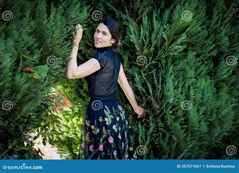 A Young Pretty Woman In Black Clothes Is Standing Near A Bush Stock Image Image Of Outside