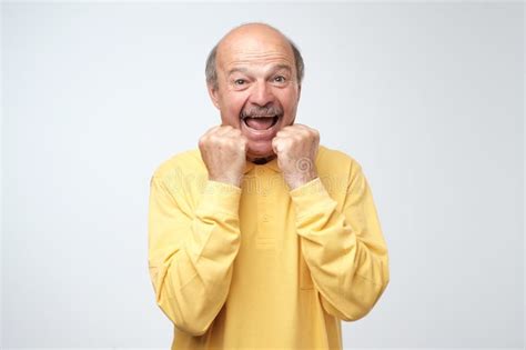 Happy Senior Man In Yellow Tshirt Celebrating His Success Over Gray