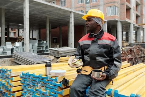 Premium Photo Restful Mature Builder With Snack And Cup Of Tea Sitting On Stack Of Materials