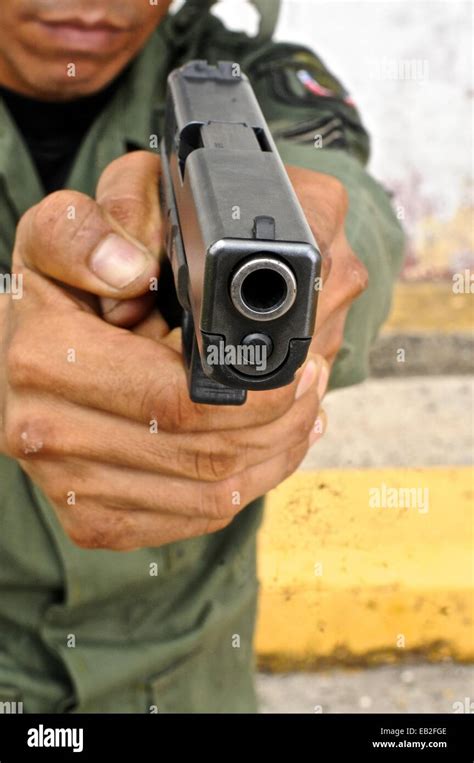 Uniformed police officer aiming a pistol at a tactical and firearms ...