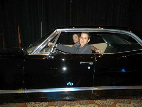 Two Men Sitting In The Driver S Seat Of A Black Car