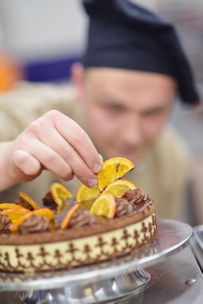 Premium Photo Closeup Of A Concentrated Male Pastry Chef Decorating Dessert Cake Food In The