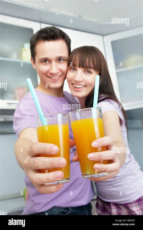 Young Cheerful Couple Drinking Orange Juice In The Kitchen Healthy