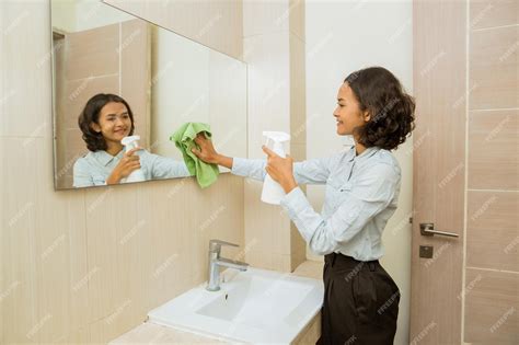 Premium Photo Janitor Cleaning The Mirror Spraying And Wiping The