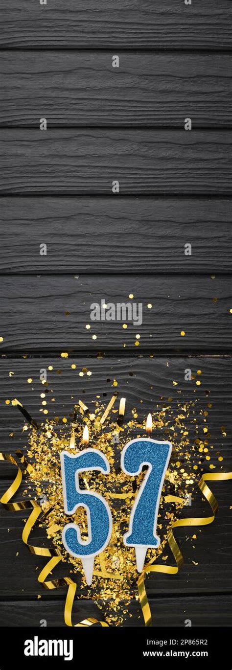 Number 57 Blue Celebration Candle And Gold Confetti On Dark Wooden