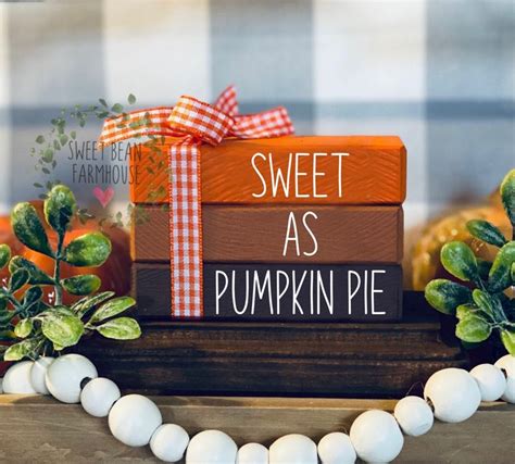 A Stack Of Pumpkins Sitting On Top Of A Wooden Block With The Words Sweet As Pumpkin Pie