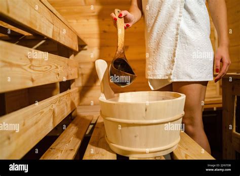 Hand Of Unknown Caucasian Woman In Sauna Spa Taking Water From Bucket With Wooden Spoon To Pour