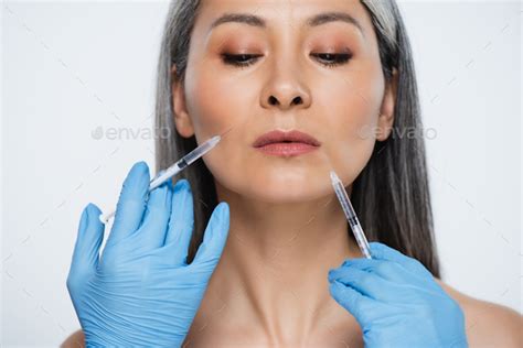Beautiful Nude Asian Woman And Doctors In Latex Gloves Holding Syringes With Beauty Injections