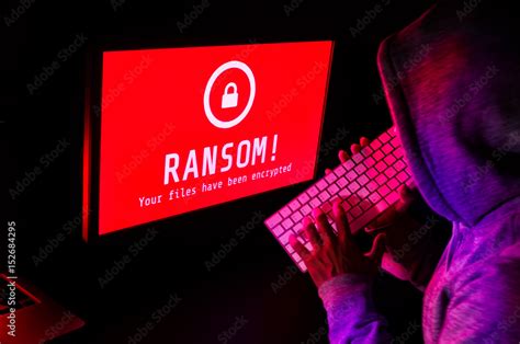 Computer screen with ransomware attack alert in red and a hacker man ...