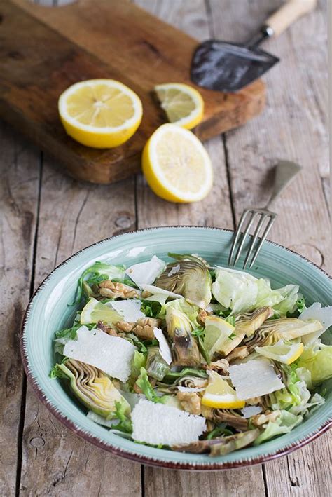 A Salad With Lemons And Parmesan Cheese In A Bowl On A Wooden Table