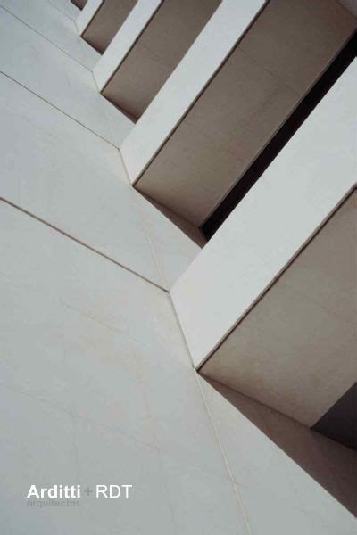 The Corner Of An Architectural Building With White Walls And Balconies