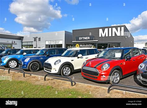 Row of used car dealers second hand BMW Mini cars for sale on garage forecourt in front of ...