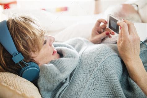 Mature Woman Lying On Bed Using Mp Player Stock Photo By Image Source