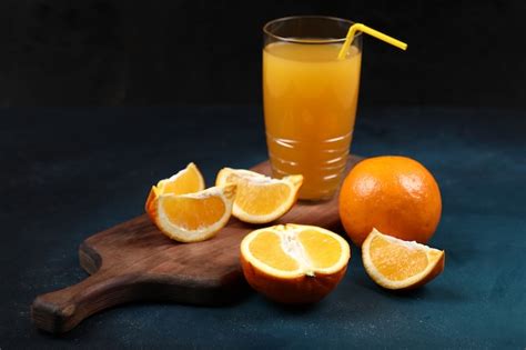 Laranjas inteiras e fatiadas um copo de suco Foto Grátis