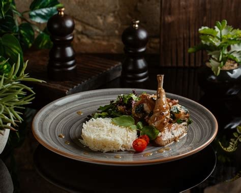 Free Photo Spicy Rice Garnish With Sauteed Chicken Legs And Greenery