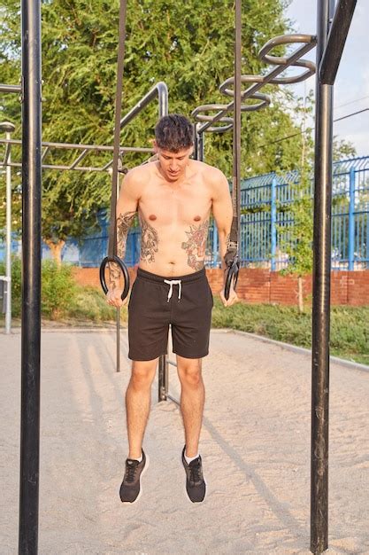 Hombre Sin Camisa Con Anillos De Entrenamiento De Tatuajes En El Parque