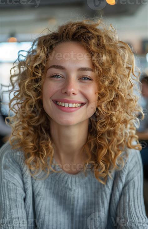 Close Up Of Laughing Curly Blonde Woman In Office With Blurred People Working In Background