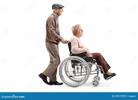 Elderly Man Pushing A Disabled Woman In A Wheelchair Stock Image