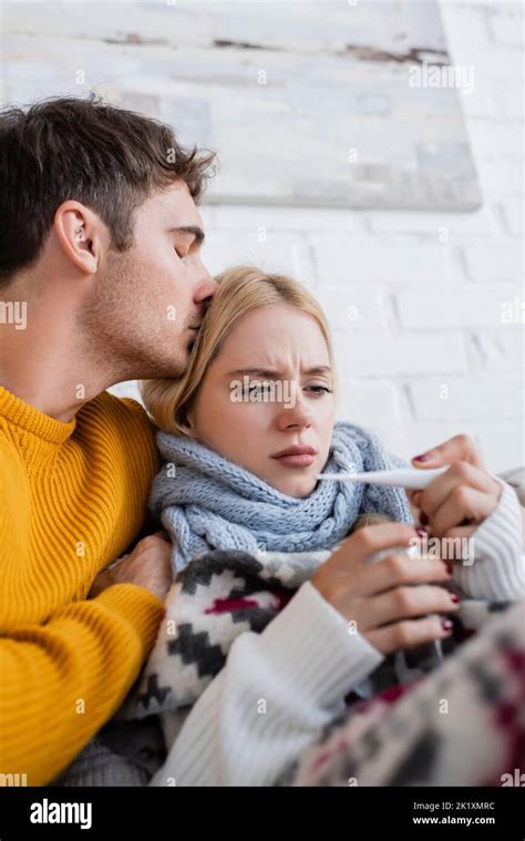 Caring Man Hugging And Kissing Head Of Sick Blonde Woman With Digital Thermometer Stock Image
