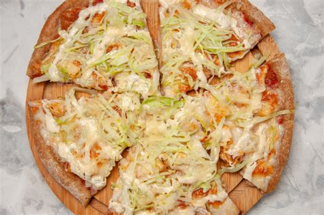 Top view of delicious vegan pizza divided into fourths on stained white background with free ...