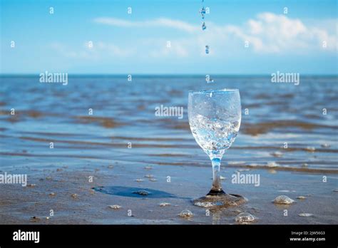 Water Pours Into A Glass Against The Background Of The Sea Clean Water