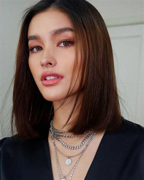 A Woman With Long Brown Hair Wearing A Black Top And Silver Necklaces