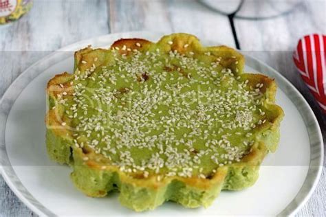 A Green Dessert On A White Plate With Sprinkles In The Center And Red