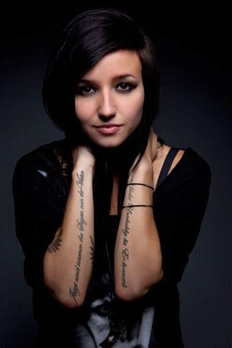 A Woman With Tattoos On Her Arms Posing For The Camera