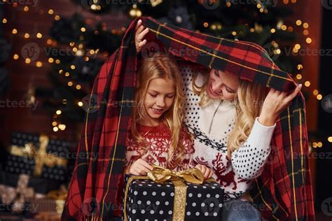 Mother And Daughter Sits Under Plaid With Ts Celebrating Christmas