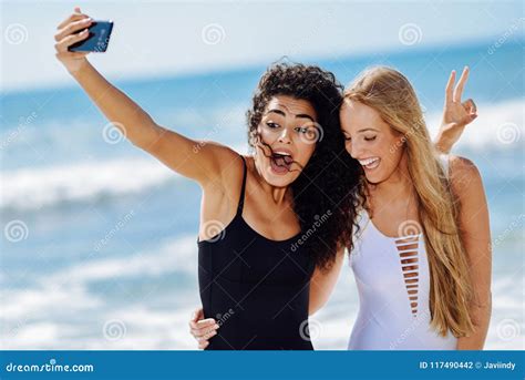 Two Women Taking Selfie Photograph With Smartphone In The Beach Stock