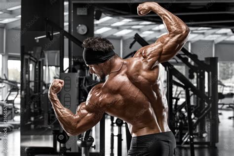 Rear View Muscular Man Showing Back Muscles And Double Biceps In Gym Strong Male Naked Torso