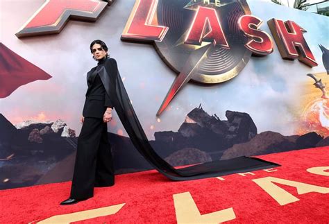 A Woman Standing On Top Of A Red Carpet In Front Of A Sign That Says