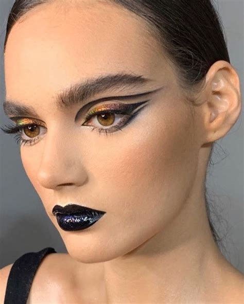 A Woman With Black Lipstick And Gold Eyeshades On Her Face Wearing