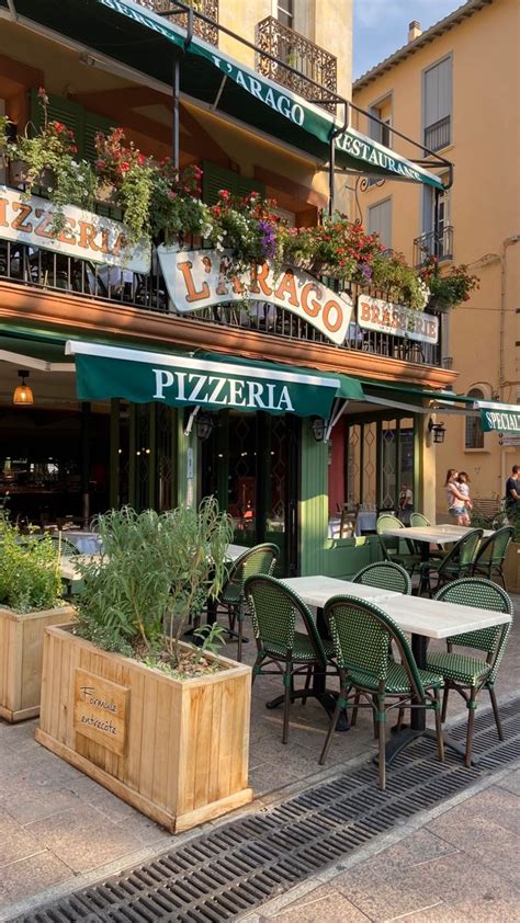 Tables And Chairs Outside An Italian Restaurant With Green Awnings On