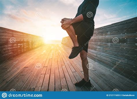 Man Stretching Legs Before Workout Outdoors At Sunset Runner Preparing