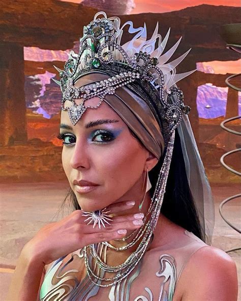 A Woman Wearing A Tiara And Jewelry In Front Of A Desert Landscape With