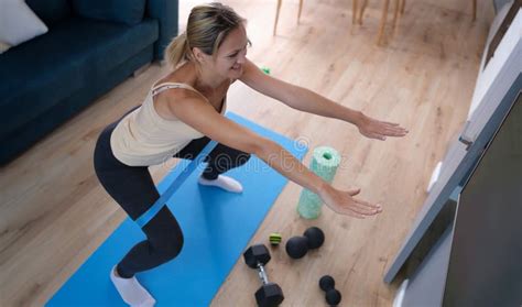 Young Woman Squatting With Elastic Band On Her Legs At Home Stock Image