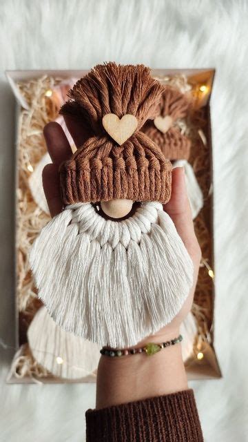 A Hand Holding A Brown And White Knitted Santa Claus Ornament